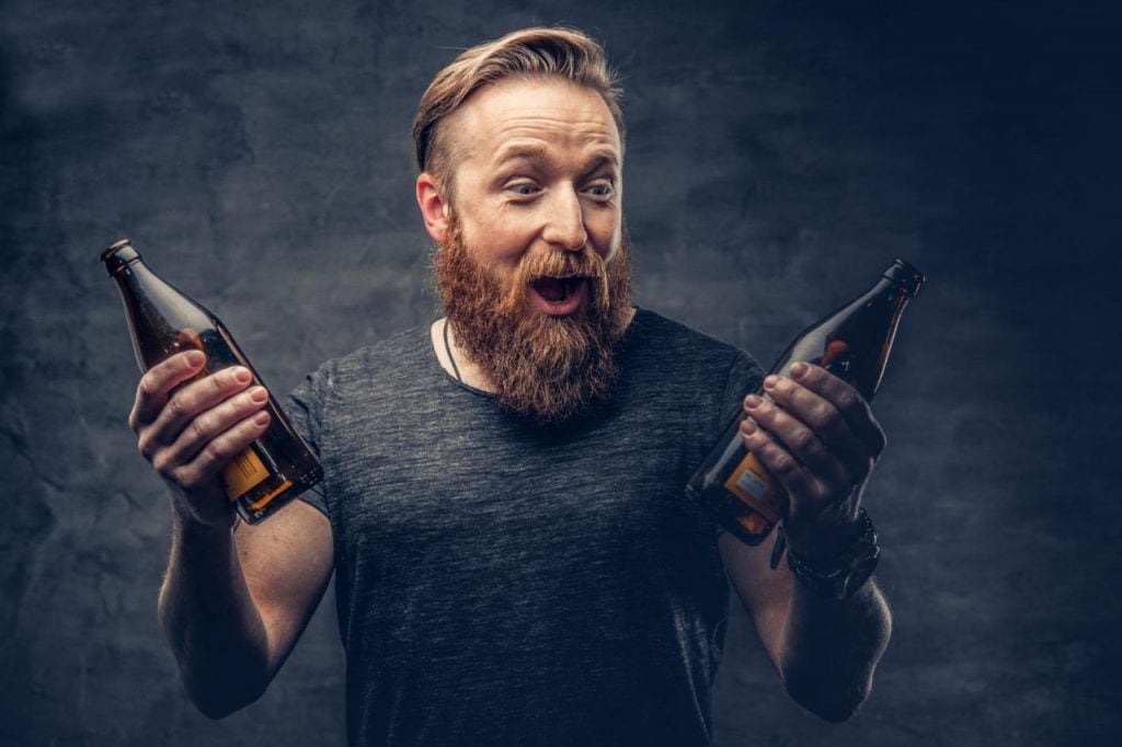 emotional funny redhead bearded drunk hipster male holds craft bottled beer 1024x682