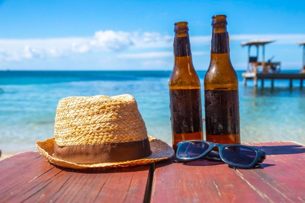 two beers sunglasses hat west end beach roatan island honduras 1024x682