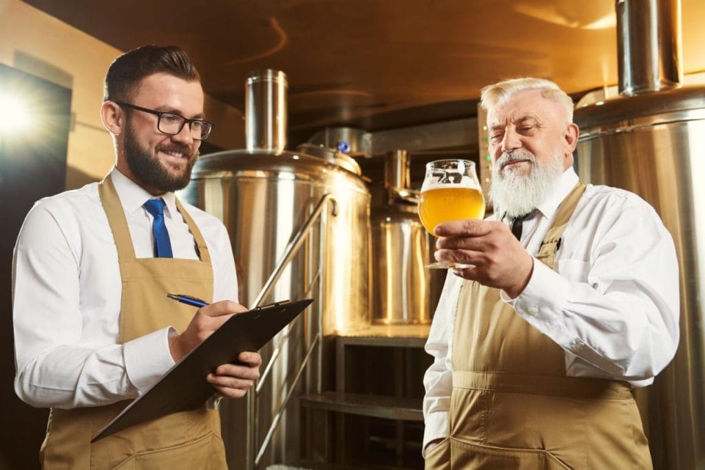 two male brewery workers examining beer 1024x683